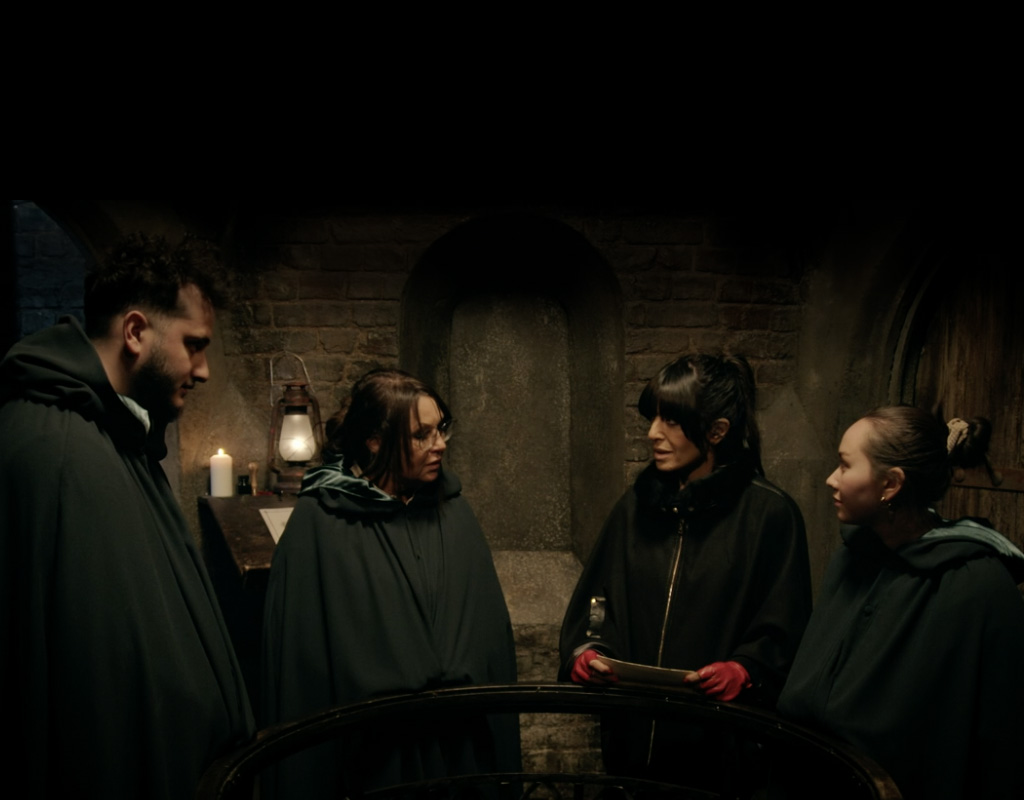 Claudia Winkleman speaks with traitors Will, Amanda and Alyssa in a scene from The Traitors